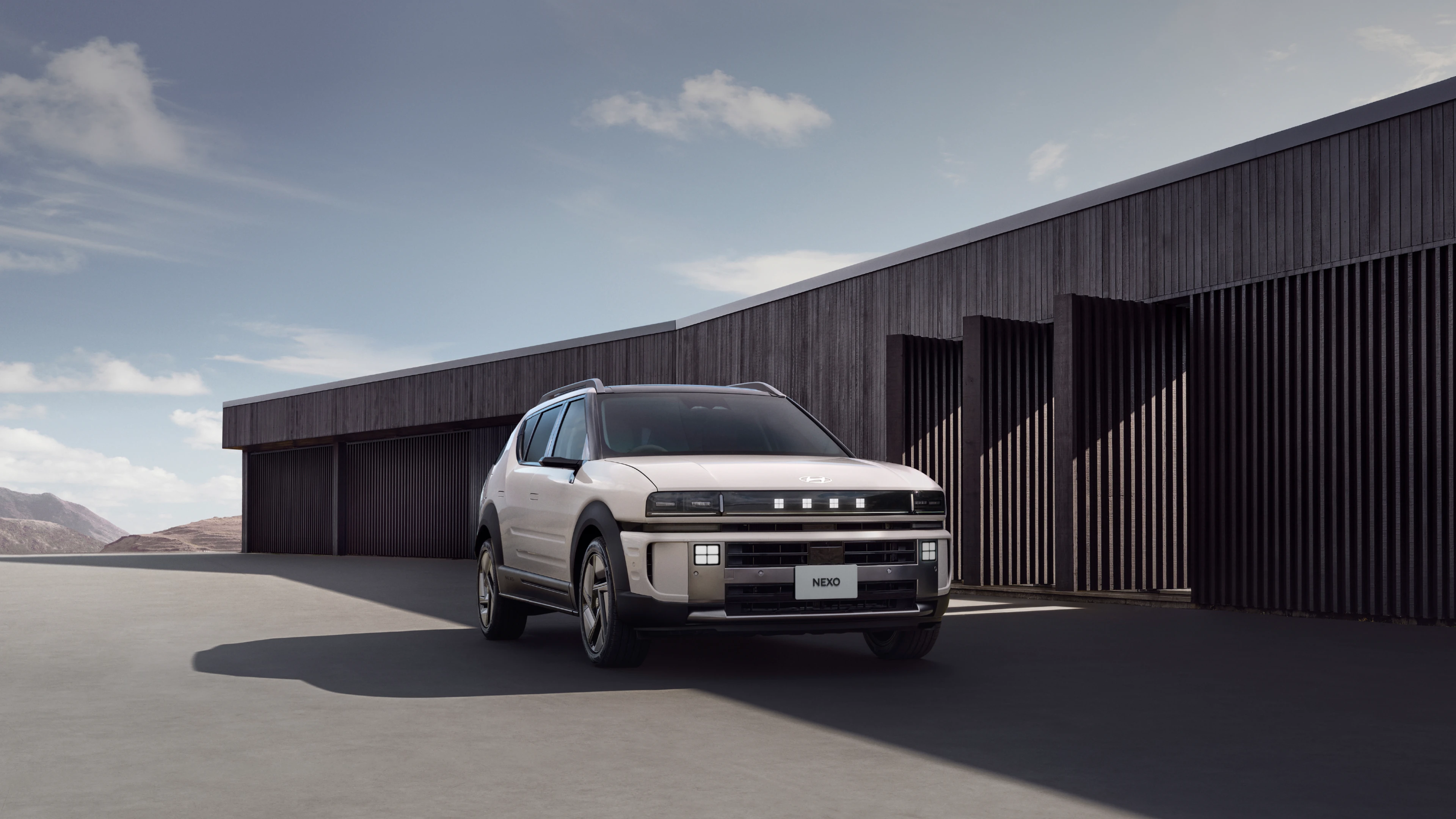 モダンな建築物を背景に建てられたThe all-new NEXOのフロントビュー - Hyundai Mobility Japan (ヒョンデ ジャパン)
