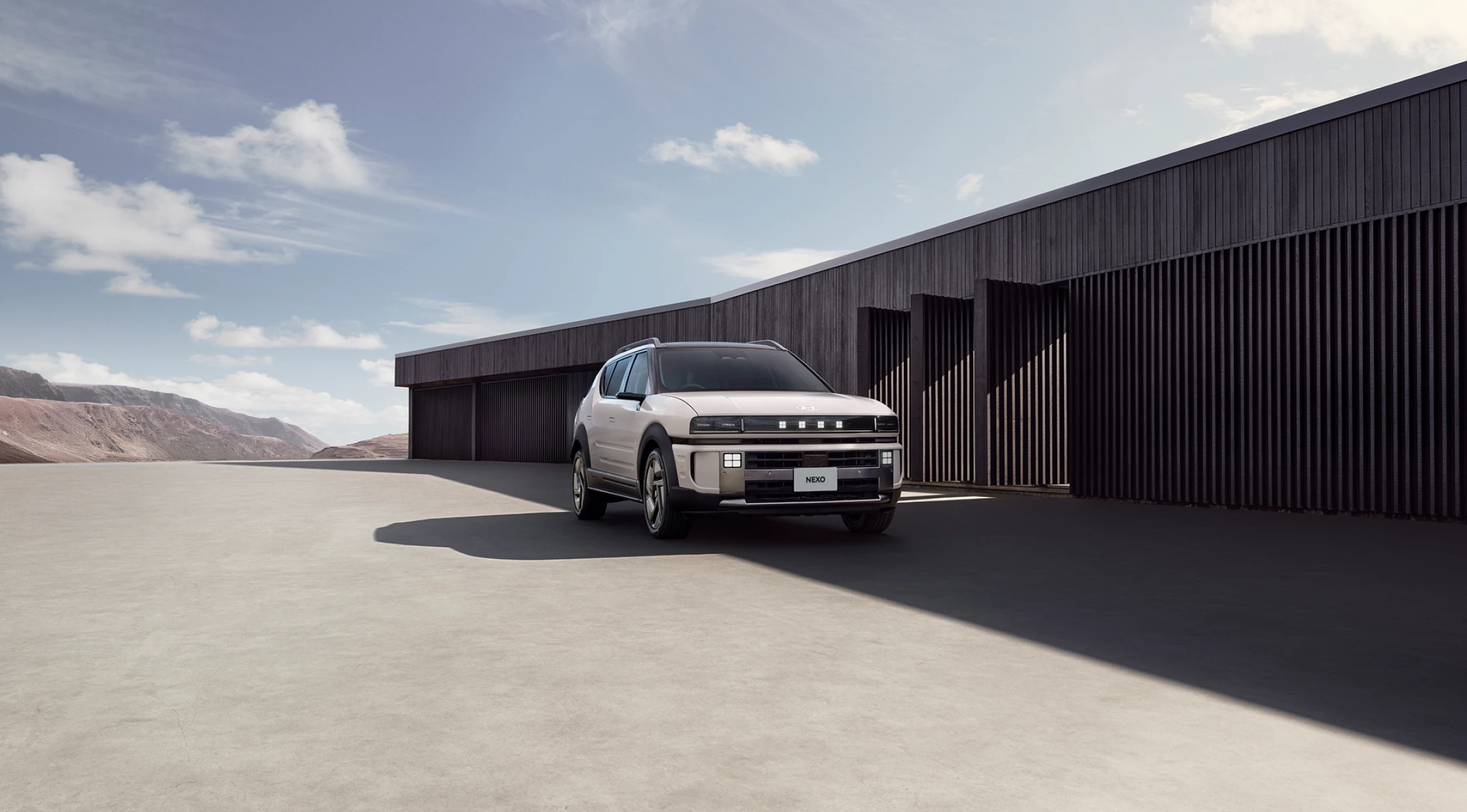 モダンな建築物を背景に建てられたThe all-new NEXOのフロントビュー - Hyundai Mobility Japan (ヒョンデ ジャパン)