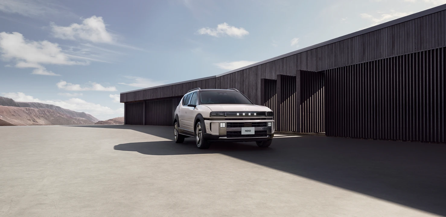 モダンな建築物を背景に建てられたThe all-new NEXOのフロントビュー - Hyundai Mobility Japan (ヒョンデ ジャパン)