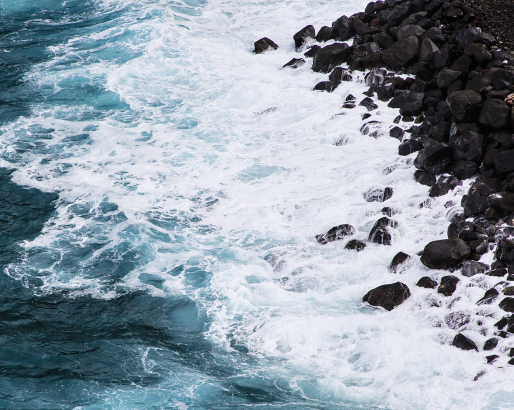 岩で白い波が砕ける真っ青な海の写真